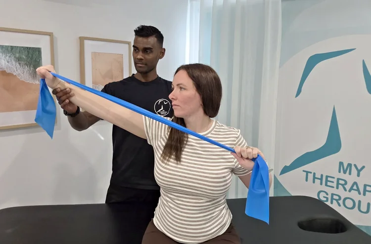 Ash guiding a resistance-band shoulder exercise.